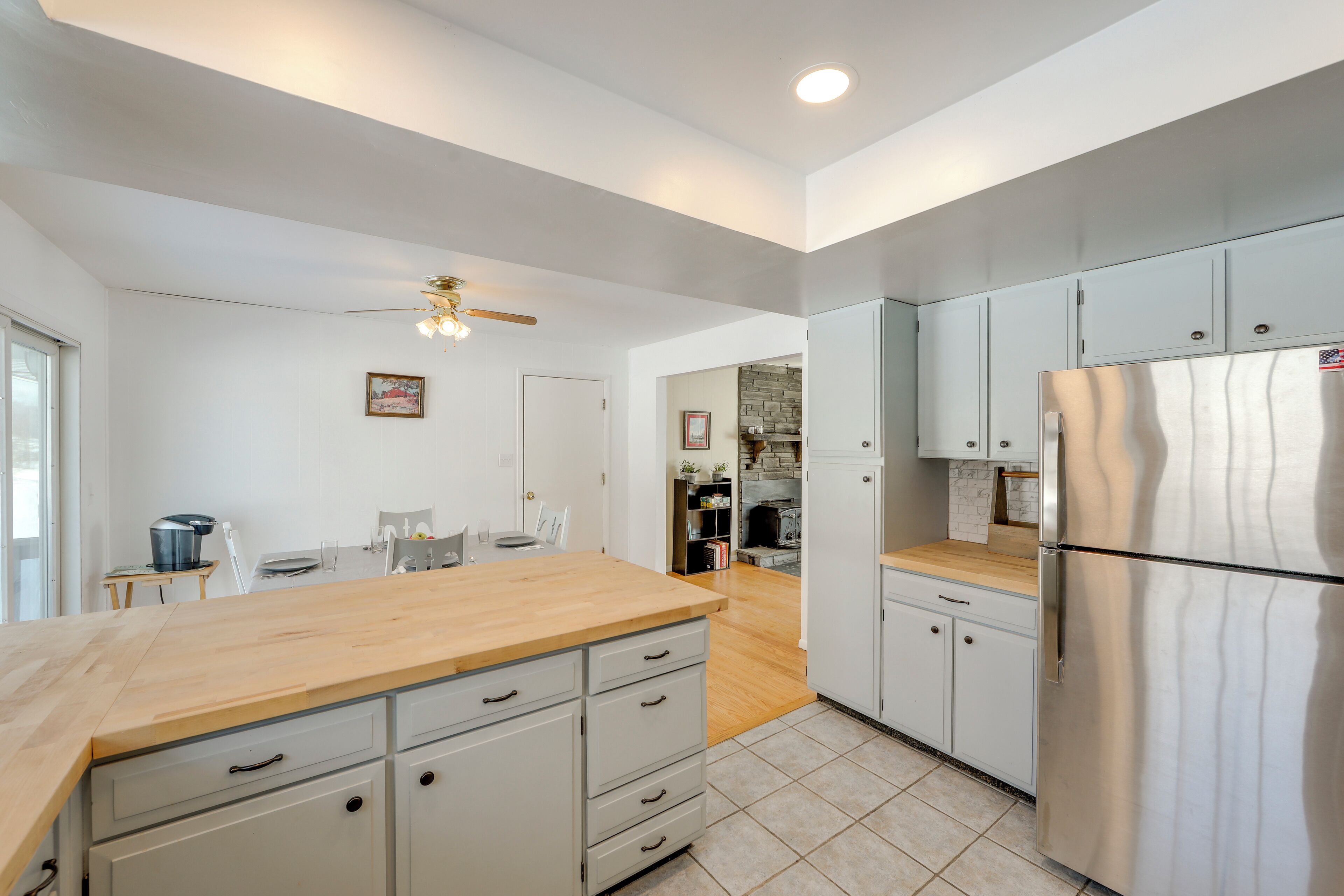 A modern kitchen with a wooden countertop, stainless steel appliances, and white cabinetry.