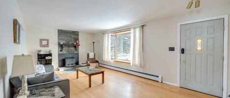 A spacious living room with hardwood flooring, a fireplace, a sofa, a coffee table, and a door with a window.