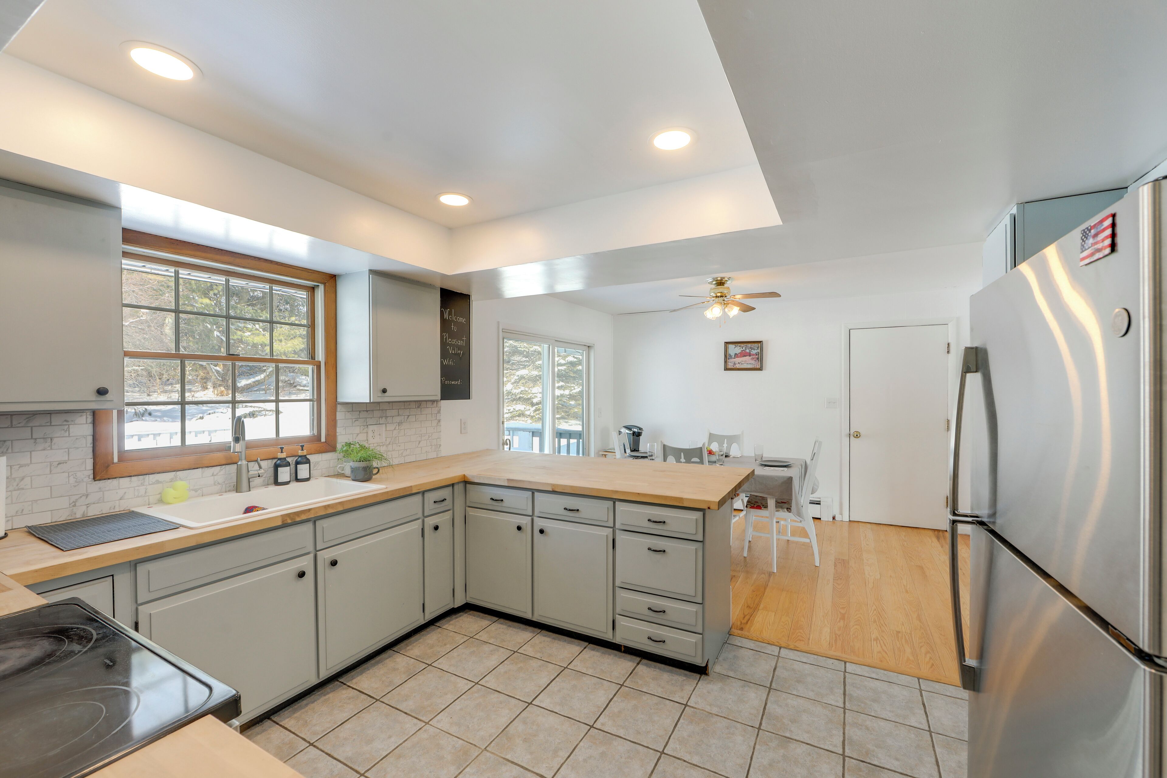 A modern kitchen with a large island, stainless steel appliances, and a dining area with a ceiling fan.