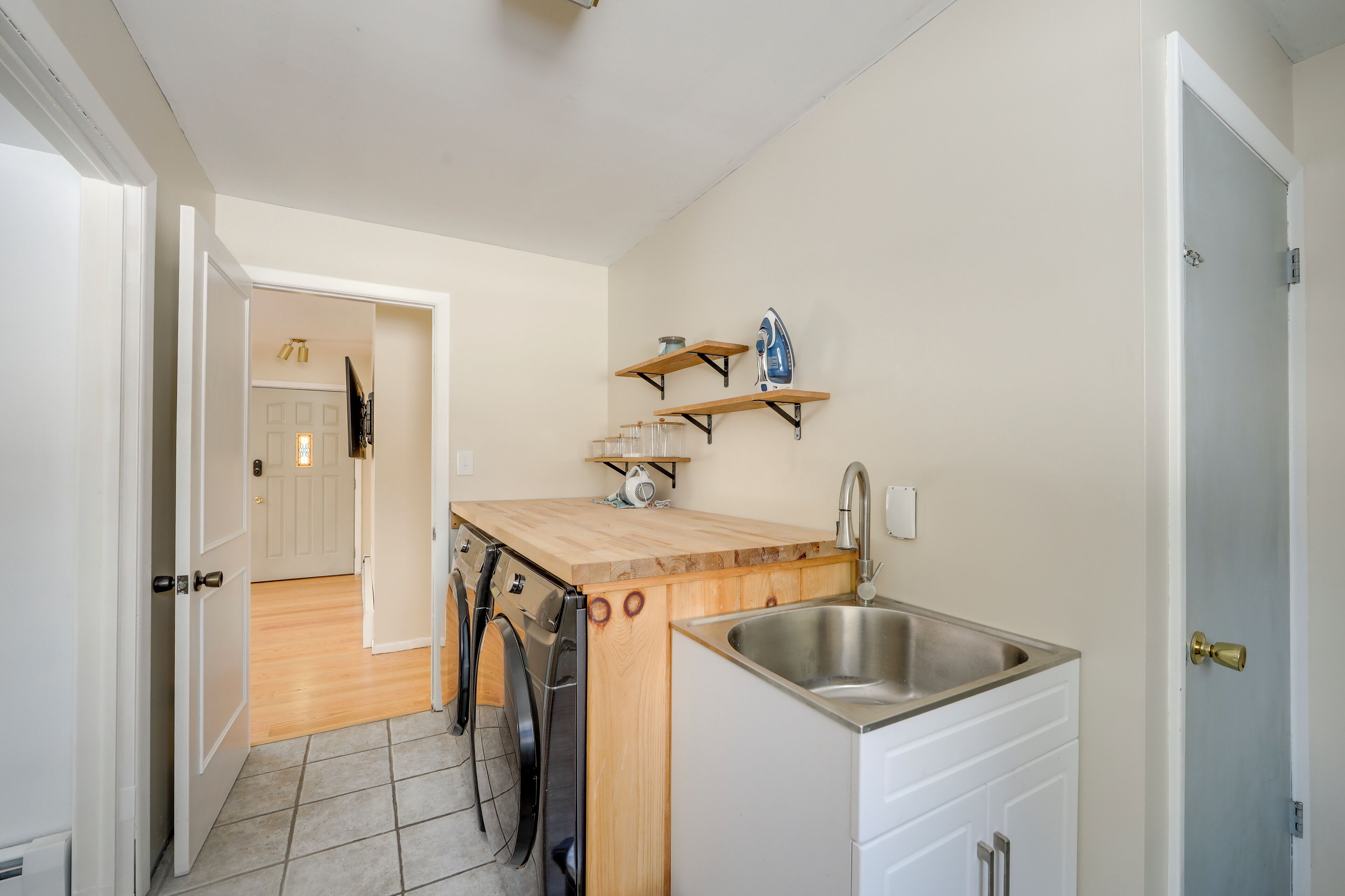 A compact kitchen with a wooden countertop, a stainless steel sink, and a washing machine.