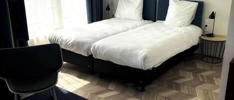 A hotel room with two beds, a desk, and a chair.