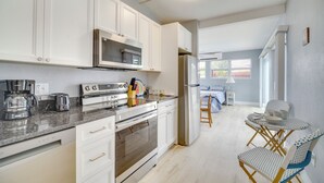 A modern kitchen with white cabinets, stainless steel appliances, and a dining area with a small table and chairs. - 5 Mi to Beaches: Melbourne Duplex w/ Heated Pool! (Melbourne)