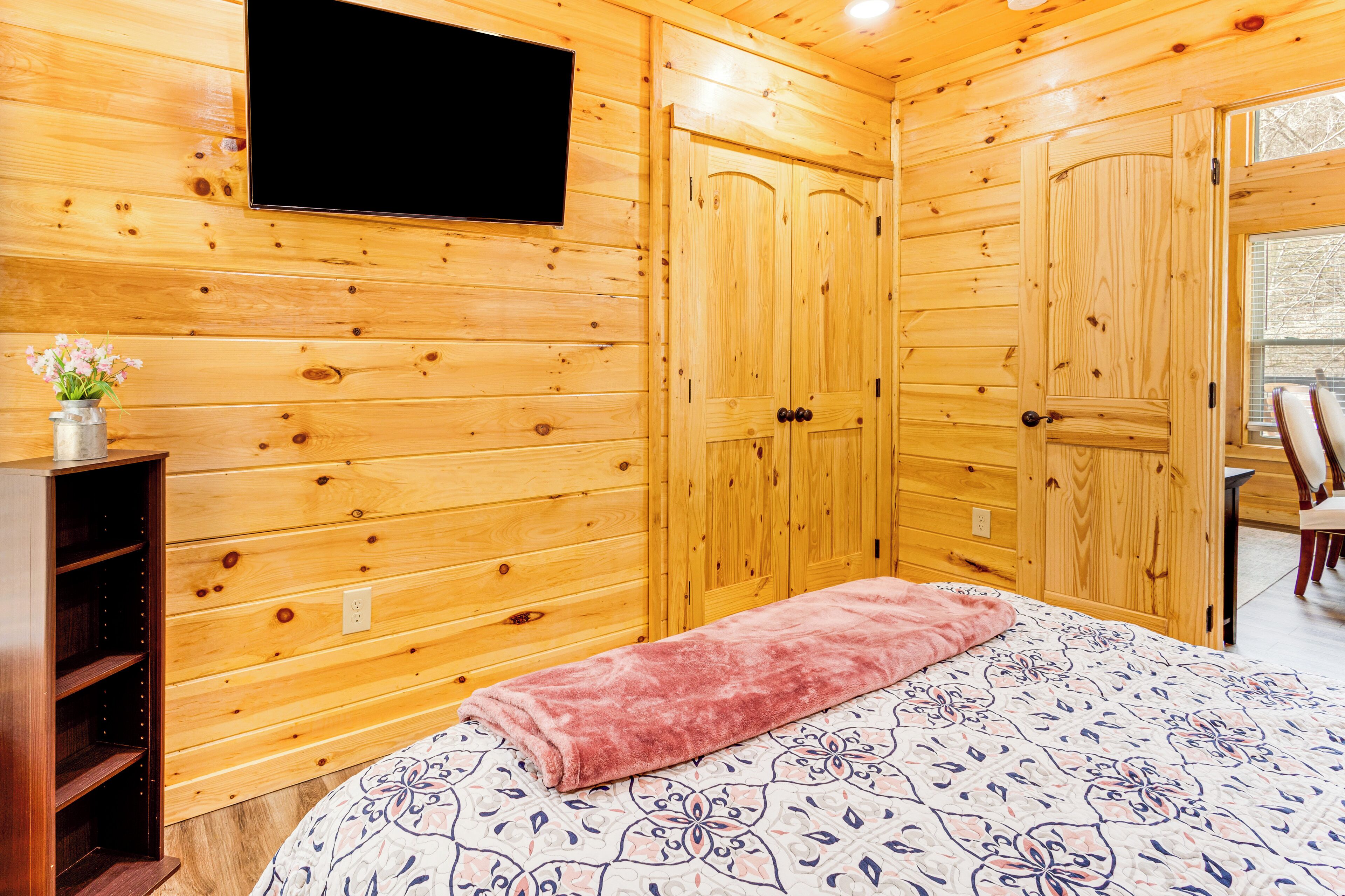 A wooden-paneled room with a bed, a television, and a wooden wardrobe.