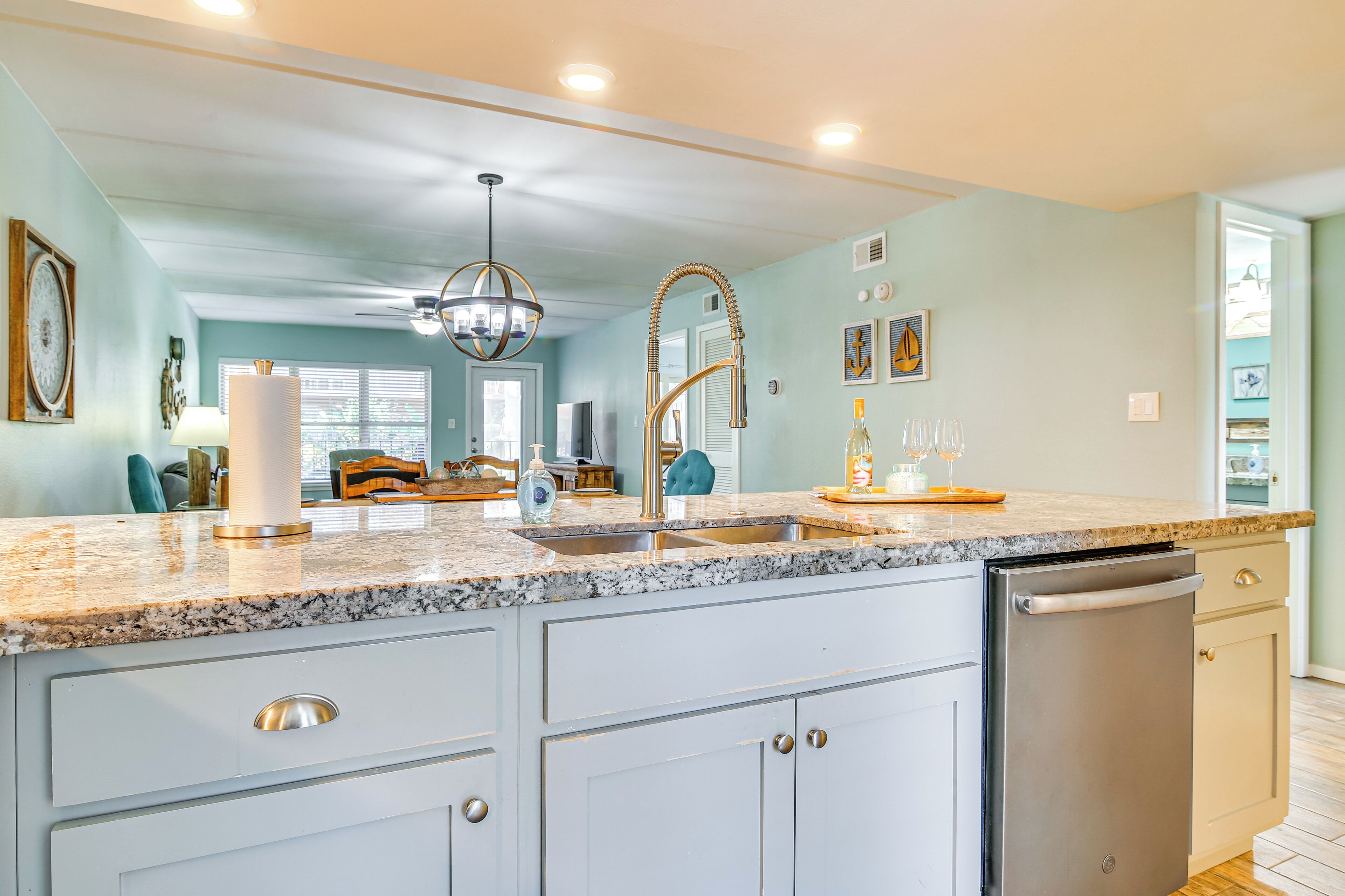 A kitchen with a granite countertop, stainless steel appliances, and a chandelier.