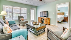 A living room with a glass coffee table, grey sofa, and a wooden cabinet. - Walk to Beach! Condo w/ Pool Access in Texas (South Padre Island)