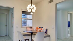 A dining area with a round table, two chairs, a bench with cushions, and a pendant light. - Tranquil Green Valley Home w/ Screened Porch (Green Valley)