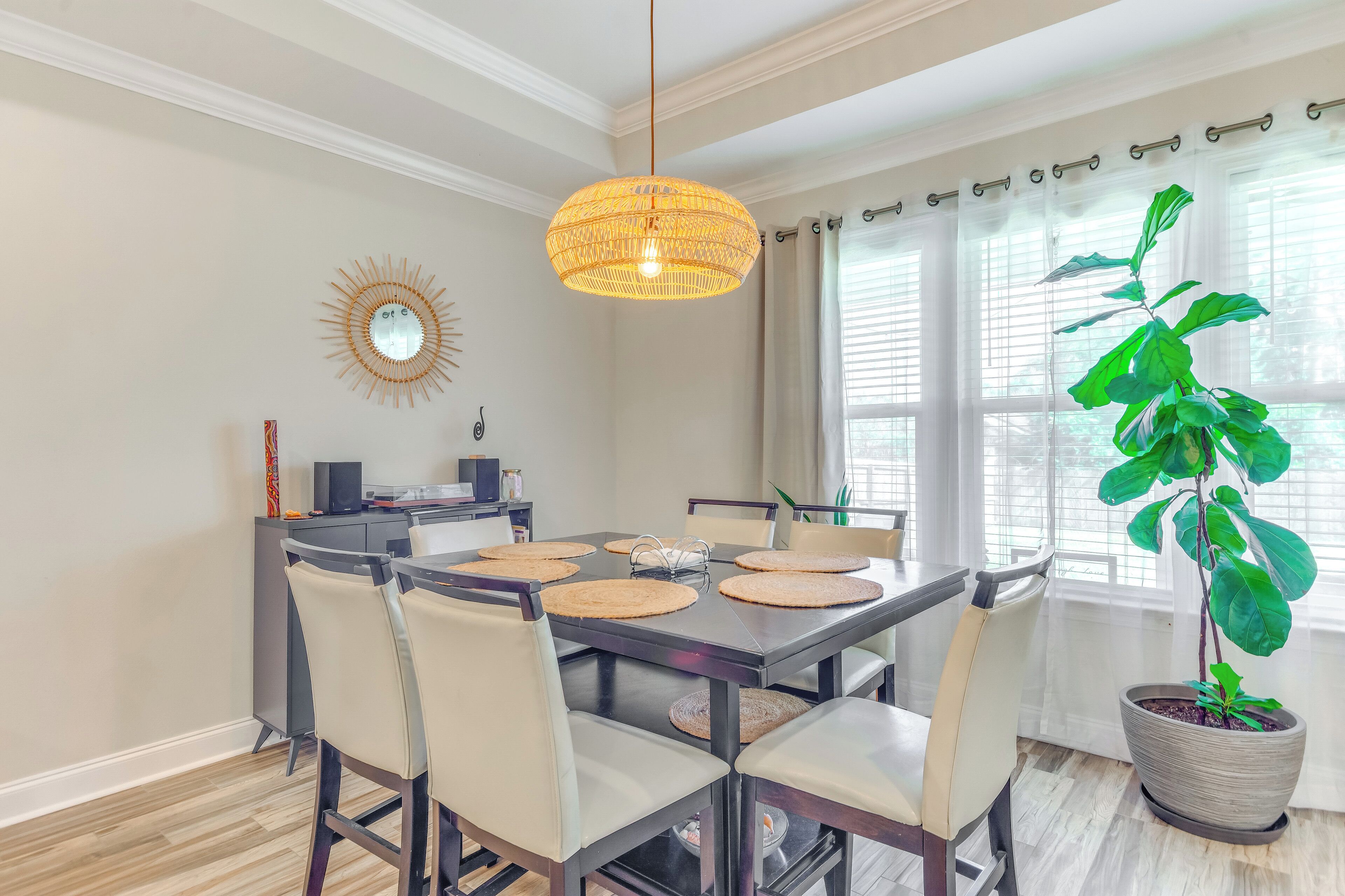 A dining area with a dark wooden table, beige chairs, and a large potted plant.