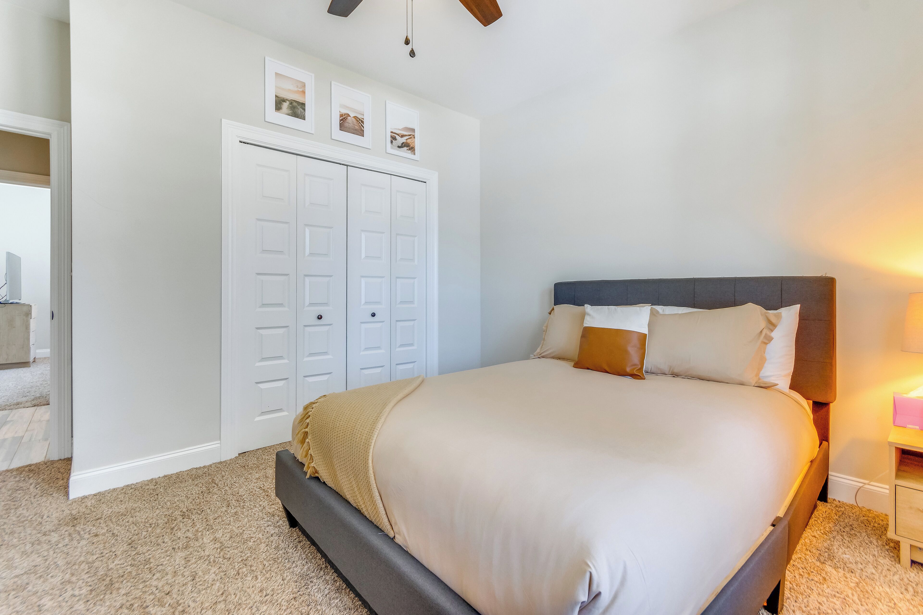 Une chambre à coucher comprenant un lit, une armoire, une table de chevet et un ventilateur de plafond.