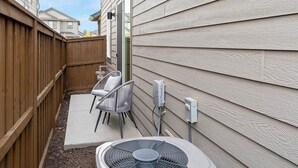 A backyard with a wooden fence, a patio with a chair, a fan, and a window. - Hike, Bike & Ski: All-season Bend Escape (Bend)