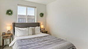 A bedroom with a large bed, two bedside tables, a window, and a view of the outside. - Hike, Bike & Ski: All-season Bend Escape (Bend)