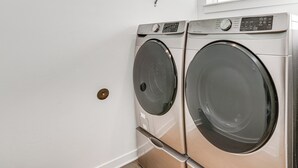 A laundry room with two front-loading washing machines and a window above. - Hike, Bike & Ski: All-season Bend Escape (Bend)