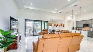 Een ruime woonkamer met een grote leren bank, een eettafel met stoelen, en een keuken met moderne apparatuur.