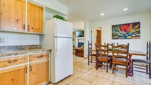 A kitchen with wooden cabinets, a white refrigerator, and a dining area with wooden chairs and a table. - Patio & Mtn Views: Wickenburg 'trail Head House' (Wickenburg)