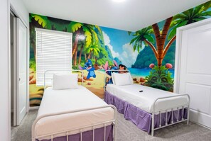 Ein Zimmer mit zwei Betten, einem Wandgemälde mit tropischer Szene und einem Fenster mit Jalousien.
