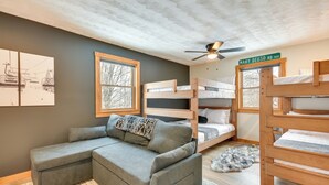 A cozy room with a gray sectional sofa, bunk beds, a ceiling fan, and a framed picture of a ski lift. - Fish, Hike & Ski: Spacious Family Escape in Eden (Eden)