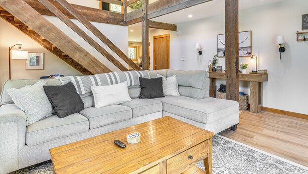 A modern living room with a grey sectional sofa, wooden coffee table, and exposed wooden beams. - Fish, Hike & Ski: Spacious Family Escape in Eden (Eden)