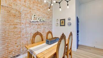 A dining area with a brick wall, wooden table, and chairs.