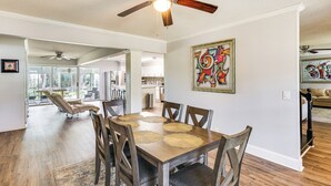 A spacious dining area with a wooden table and chairs, a ceiling fan, and artwork on the walls. - 10 Mi to St Simons Island: Home w/ Screened Porch (Brunswick)
