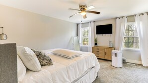A bedroom with a bed, a ceiling fan, a dresser, a TV, and a window with curtains. - 10 Mi to St Simons Island: Home w/ Screened Porch (Brunswick)