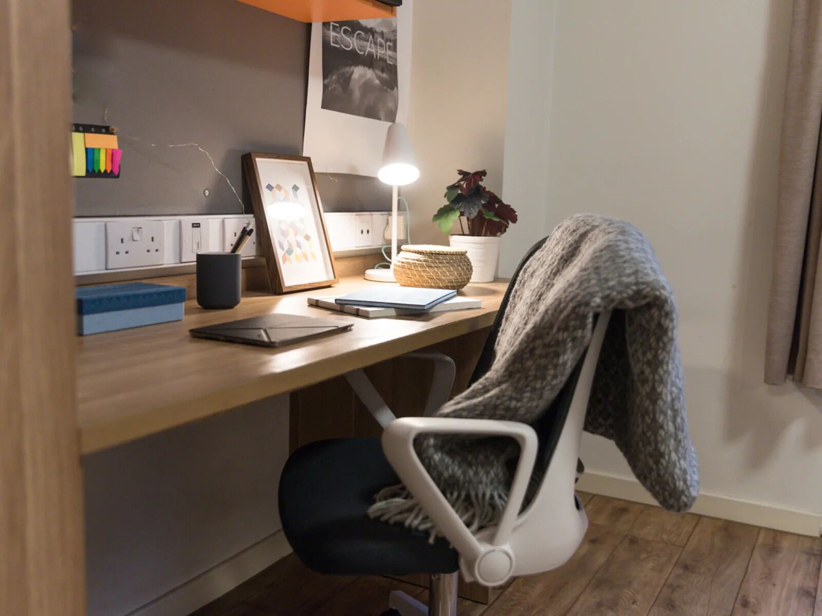 A modern office space with a desk, chair, lamp, and various office supplies.