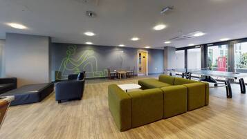 A modern lounge area with seating, a ping pong table, and a mural on the wall.