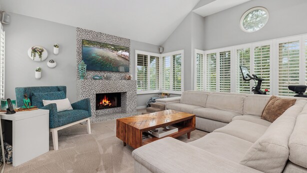 A living room with a fireplace, a sofa, a coffee table, and a TV mounted on the wall.