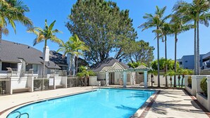A rectangular swimming pool with a brick border, surrounded by a paved deck.