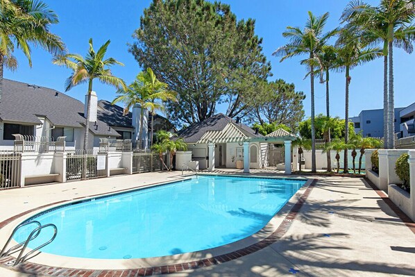 A rectangular swimming pool with a brick border, surrounded by a paved deck.