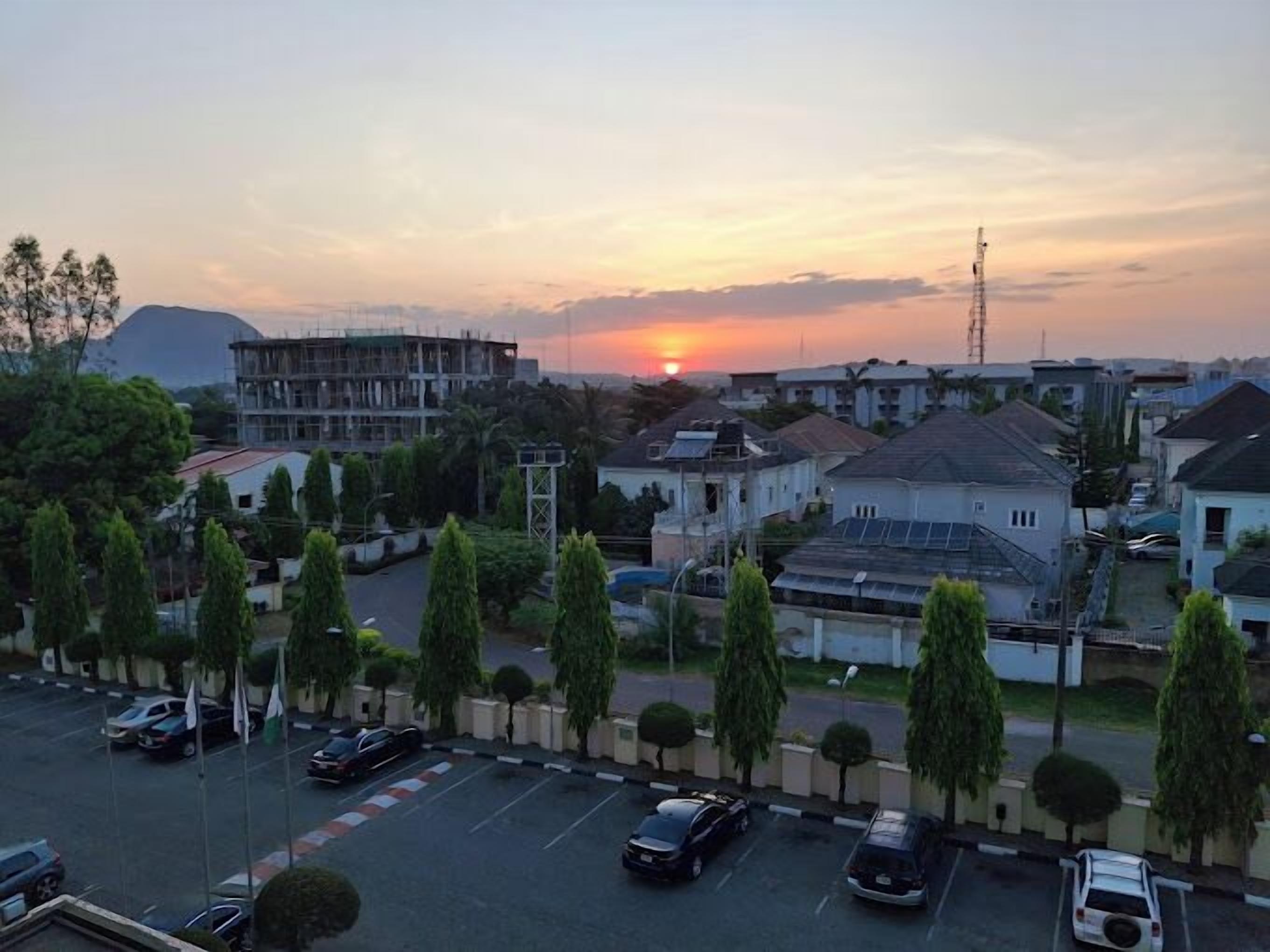 A residential area with houses, a parking lot, and a sunset in the background.