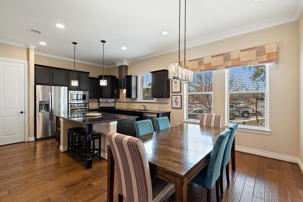 A modern kitchen with dark cabinets, stainless steel appliances, and a central island with bar stools.