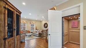 A spacious living room with a wooden cabinet, a white door with a motivational note, and a staircase leading to an upper level. - Bend in the River - Gorgeous 4-Level Brownstone with Rooftop Views (Georgetown)