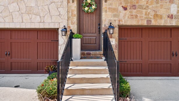 A stone building with a wooden front door, two garage doors, and a set of concrete steps leading to the entrance. - Bend in the River - Gorgeous 4-Level Brownstone with Rooftop Views (Georgetown)