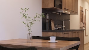 Une cuisine moderne avec des meubles en bois, un four encastré et un coin repas comprenant une table et des chaises.