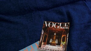 Two magazines, one titled 'VOGUE TRAVEL' and the other 'VOGUE', placed on a dark blue fabric surface. - Neon 45 Apartment - ProperUNIT (Wroclaw)