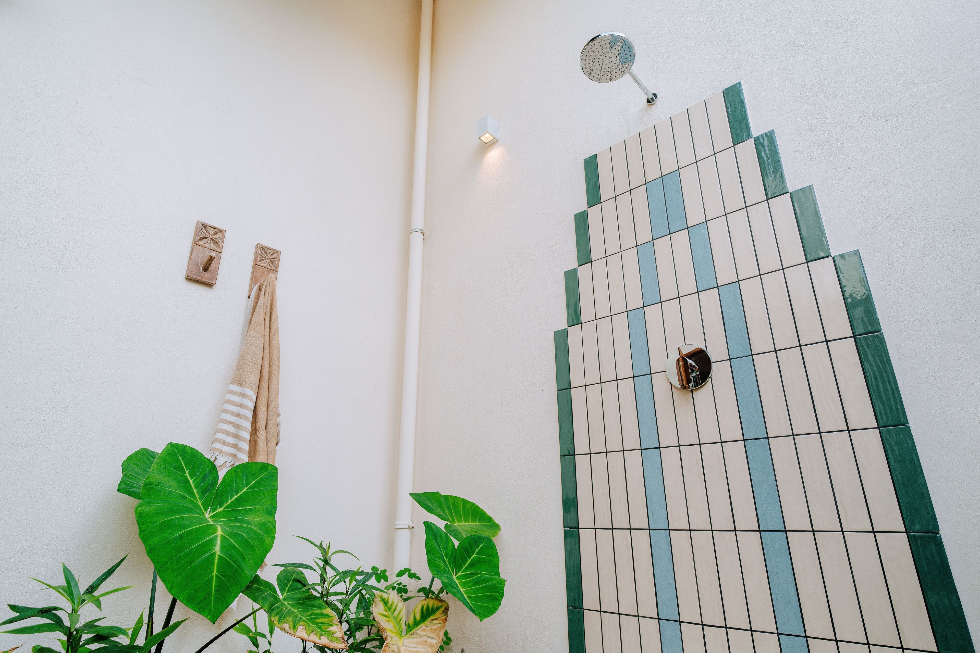 A tiled wall with a showerhead and a towel rack.