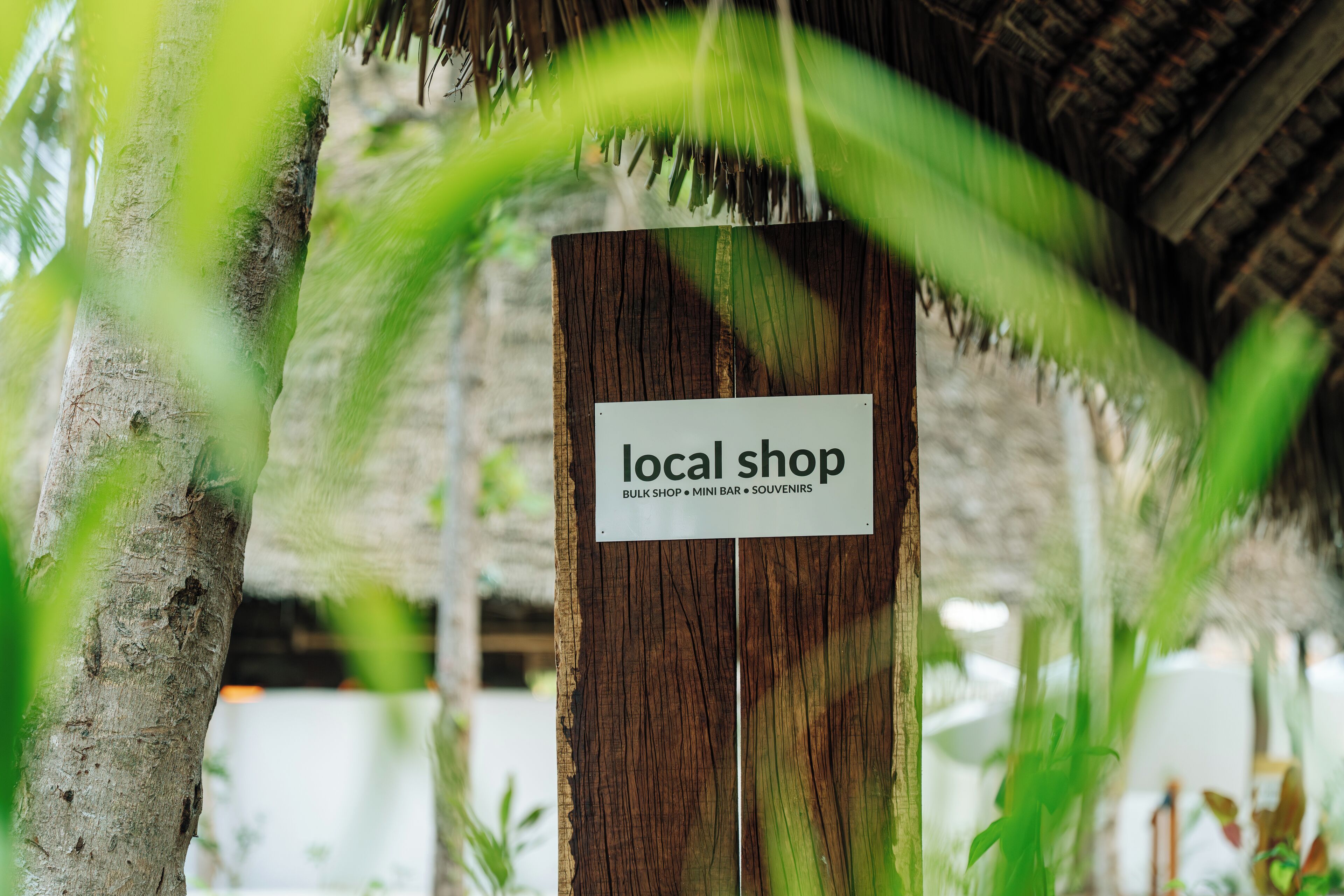 A sign for a local shop with a wooden background and a white label.