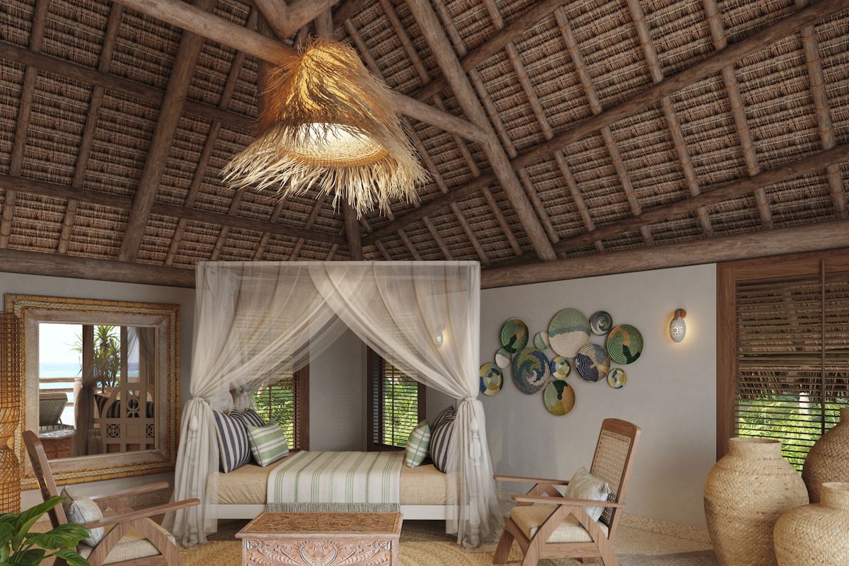 Una habitación con techo de paja, una cama con dosel, un tapete redondo tejido y una pared con platos decorativos.