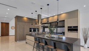 A modern kitchen with a central island, pendant lighting, and built-in appliances.