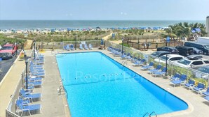 A pool area with lounge chairs, a clear view of the ocean, and a fenced beach area. - 2 Bedroom Condo with Outdoor Pool and Beautiful Ocean Views! (Ocean City)