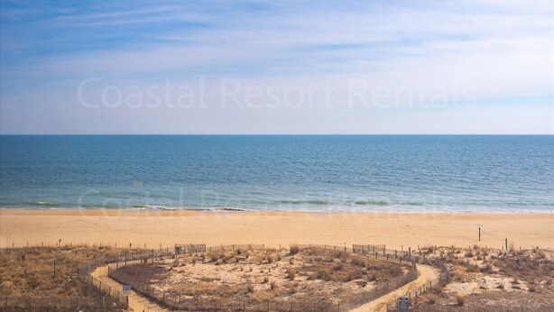 A beach with a fenced area and a clear view of the ocean. - 2 Bedroom Condo with Outdoor Pool and Beautiful Ocean Views! (Ocean City)