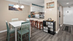 A coastal-themed kitchen with white cabinets, a black countertop, and a hanging light fixture. - 2 Bedroom Condo with Outdoor Pool and Beautiful Ocean Views! (Ocean City)