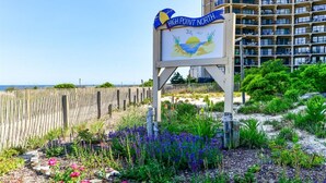 A sign for High Point North with a beach view, surrounded by a wooden fence and various plants. - HPN-1 Bedroom Oceanfront Condo, Steps to the Beach! (Ocean City)
