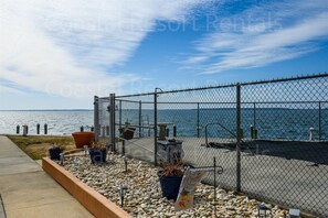 Enjoy a serene coastal retreat with a walkway leading to a gated entrance and scenic sea views.