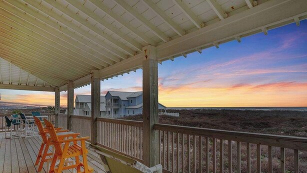 A wooden deck with outdoor furniture, overlooking a beach and houses in the distance. - Amazing Beach Views~Boardwalk to Beach~Shared Pool (Port Aransas)