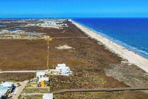 Une vue aérienne d’une zone côtière avec une plage, des bâtiments et une route.