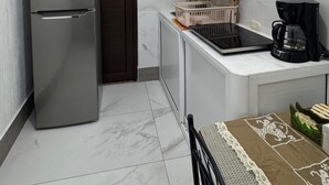 A compact kitchen with a refrigerator, microwave, stove, and coffee maker.