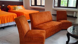 A hotel room with two beds, a sofa, and a glass-top table.