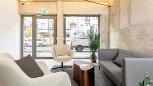 A modern waiting area with a sofa, armchair, and a coffee table. - Global Living I The Graf (Berlin)