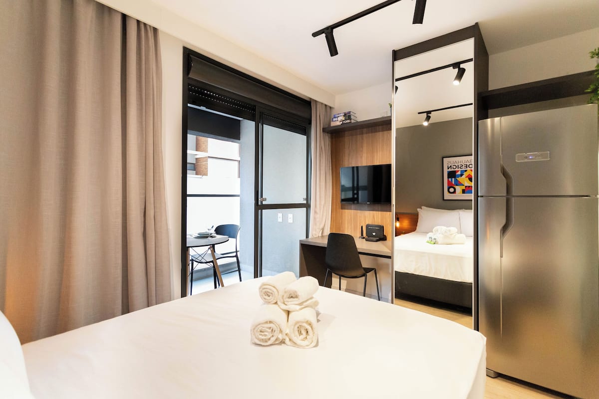 Een hotelkamer met een bed, een bureau, een stoel, een televisie en een koelkast.