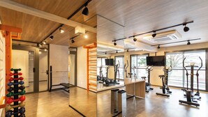 Un gimnasio moderno con equipo de ejercicio, un muro de espejos y amplias ventanas.